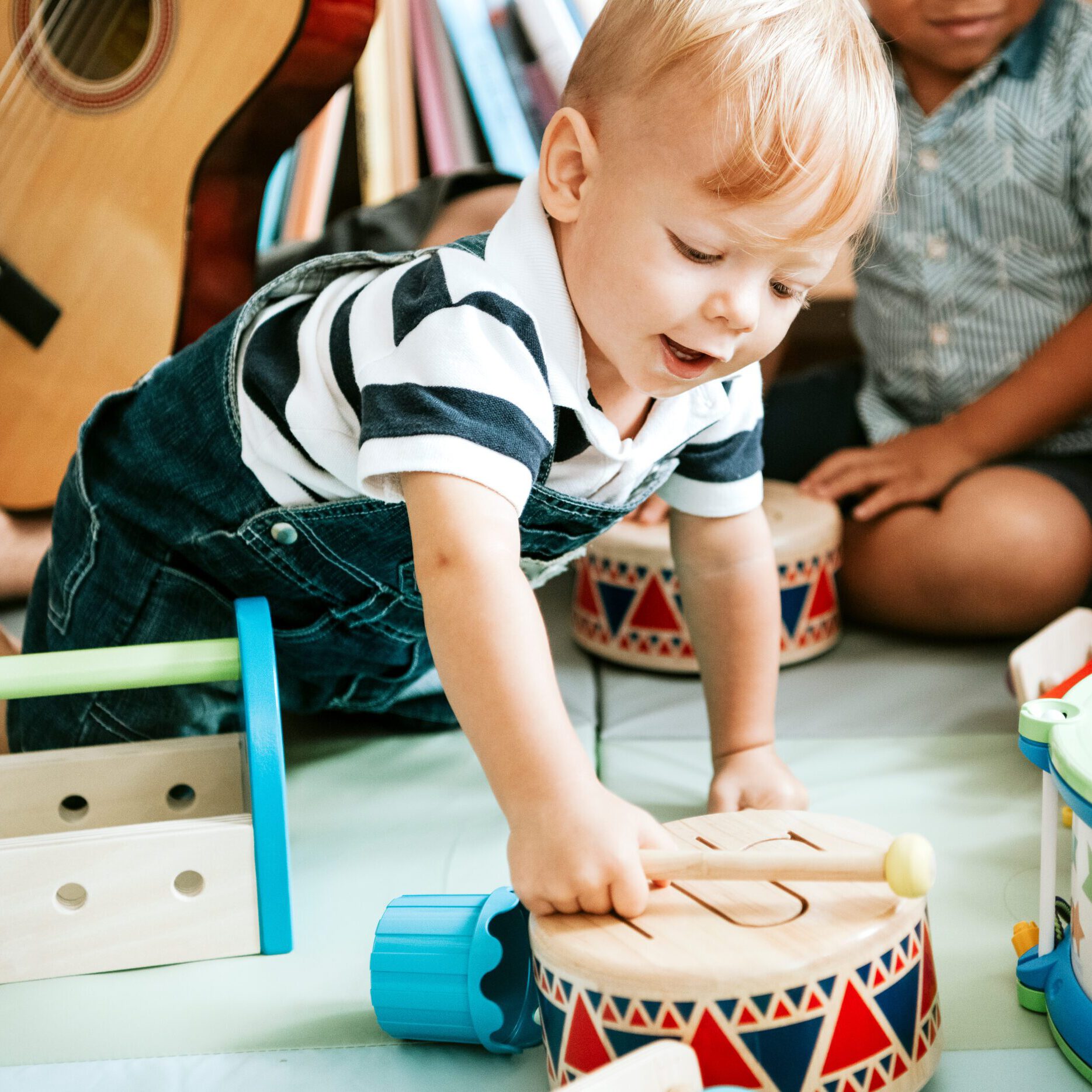 Little kid playing with a wooden drum set